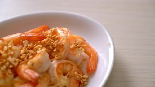 fried shrimps or prawns with garlic on white plate - seafood style