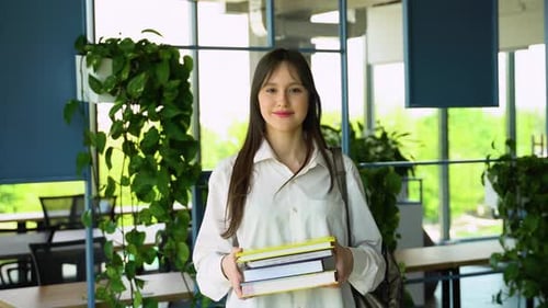 Portrait of an College Girl Student with Books in Hands in the University Building Back to School