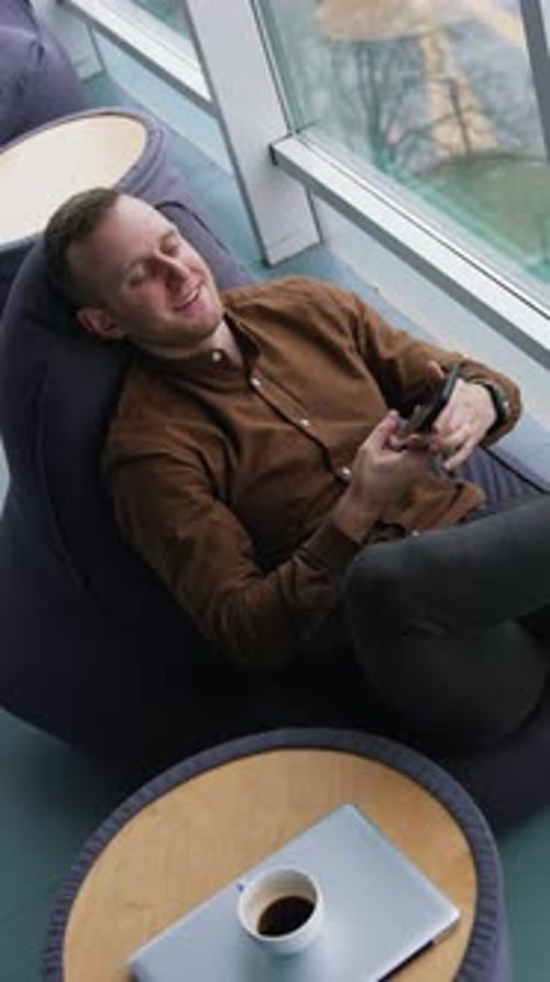 Man Relaxing, Lying on Beanbag Chair with Phone