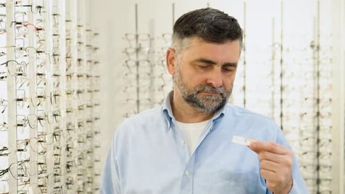 Hombre mayor de 50 años y 60 sostiene lentes de contacto en las manos