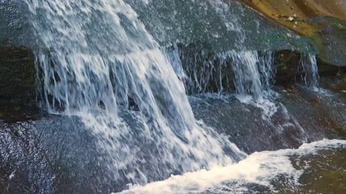 A Small Mountain Stream with Fast Moving Clear Water Between Rocky Stones in Autumn