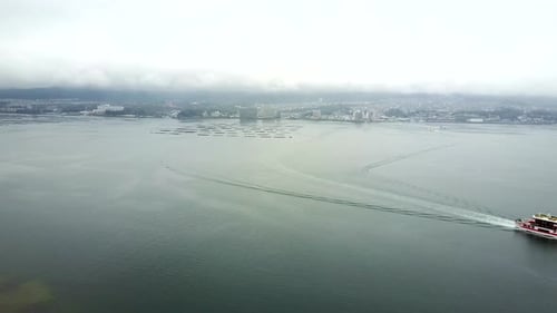 Drone shot approaching the impressive and touristy bay of the Tai Mei Tuk reservoir while a ferry tr
