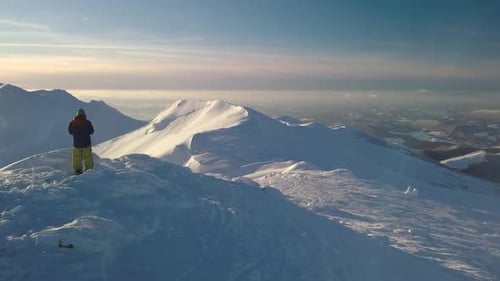 Man Standing on Top of Snowy Peak in Winter Mountains
