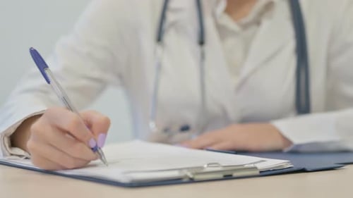 Nahaufnahme einer Ärztin, die Papierkram erledigt und einen medizinischen Bericht schreibt