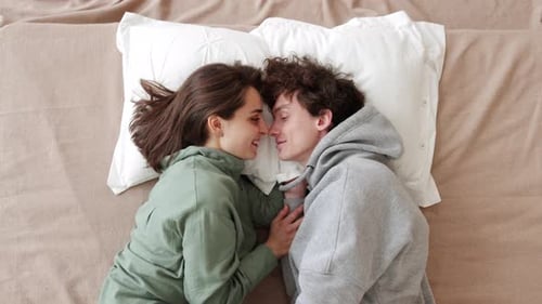 Couple Lying on Bed Kissing Overhead Shot