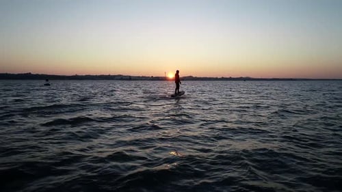 E Foil Sunset boating on the water. Paddleboard, stand-up surfing on electric foil. Aerial drone sho