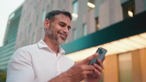 Man Using Phone Outside Building in City