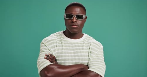 Black man, fashion or sunglasses with confidence in studio for style or swag on a green background