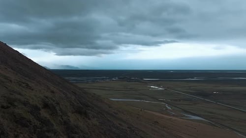 Rainy day in Iceland flying along a volcanic mountain towards a lava field