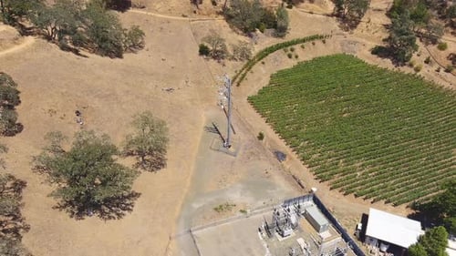 Towering Electric Metal Pole With Sight Of Another Downed Powerline Beside A Power Station. Aerial