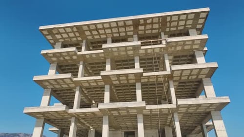 Vídeo aéreo de un sitio de construcción industrial con una gran fachada de edificio y un pintoresco paseo marítimo
