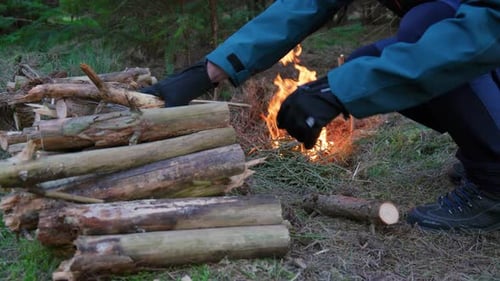 Homme utilisant de petites bûches de bois pour brûler dans la forêt de Norfolk pendant la soirée.