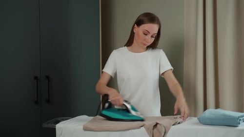 Woman Ironing Clothes on Ironing Board at Home