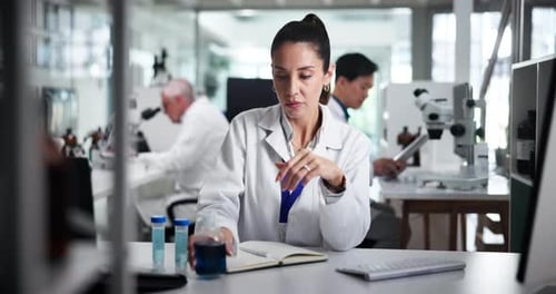 Woman Scientist Examining Blue Liquid in Laboratory