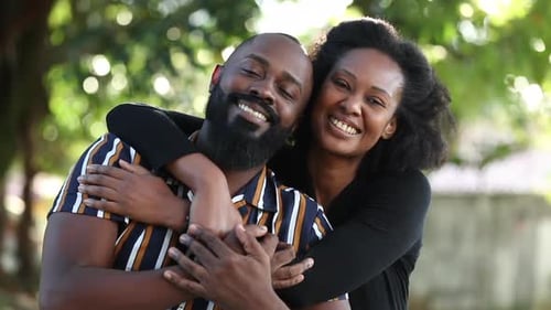 African couple embrace looking at camera. Black diverse partners hugging at park
