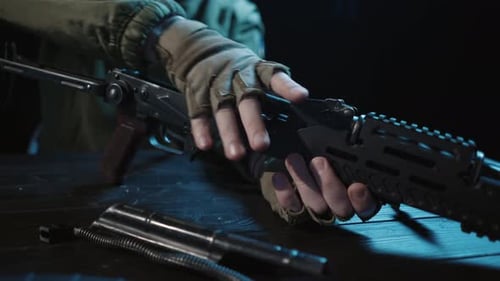 Montage de tous les détails du fusil d'assaut Kalachnikov sur une table en bois, gros plan des mains d'un homme
