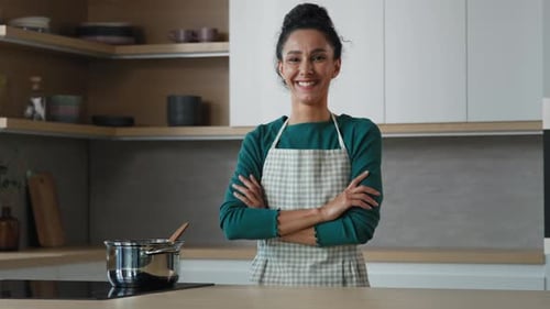 Cheerful Beautiful Woman Wears Apron Standing in Modern Kitchen with Crossed Hands Smiling Happy