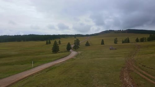 Aerial View of a Dirt Road Among Meadows in Rainy Weather