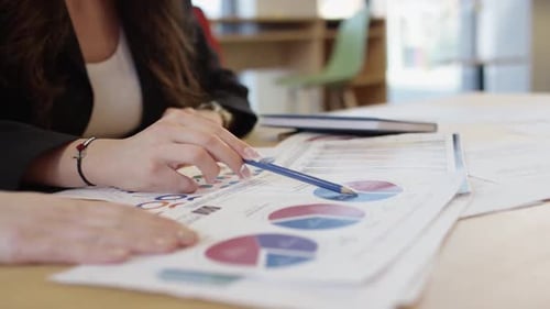 Woman Analyzes Charts with Pencil at Office Table
