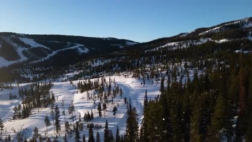 A drone shot of snowy Big Sky, Montana in winter, showcasing the ski resort and majestic mountain te