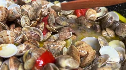 Mélangez de délicieuses palourdes fraîches, des poivrons et des tomates à l'aide d'une fourchette en bois dans une poêle chaude. Traditionnel