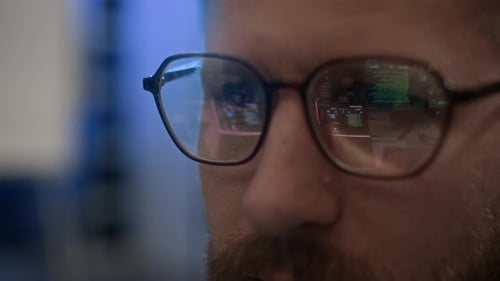 Engineer Working on Computer with Codes Reflecting in Glasses