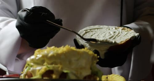 Chef Preparing Gourmet Sandwich with Spoonful of Sauce