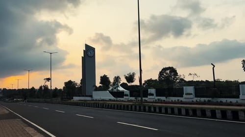 Monumento com relógio na Avenida Soraba durante o pôr do sol, motociclista passando, Índia. Portátil