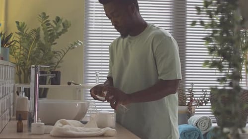 Young Man Performing Skincare Routine in Bright Bathroom
