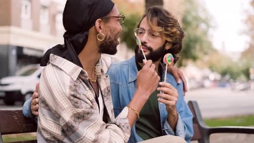 Gay Couple Eating a Lollipop Sitting in the Street