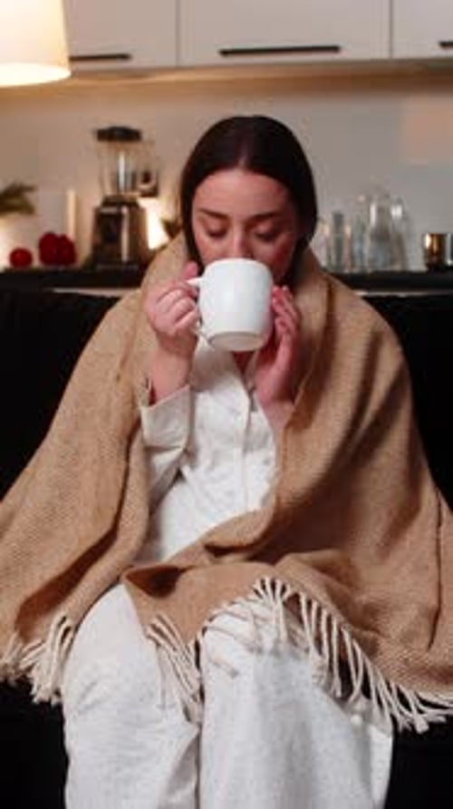Woman Enjoying Hot Drink Wrapped in Blanket Indoors