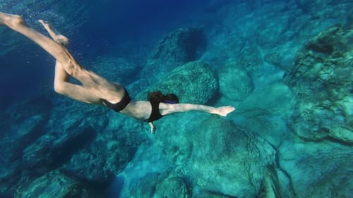 A Woman Snorkels in a Mask and Dives Under Water in the Ocean