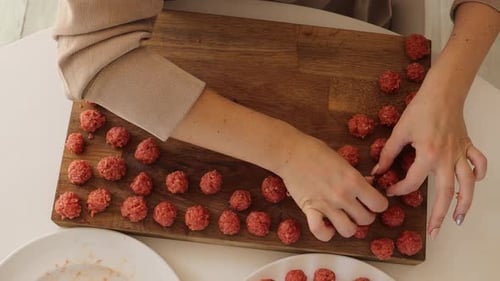 Woman Rolling Delicious Red Meatballs On Wooden Board