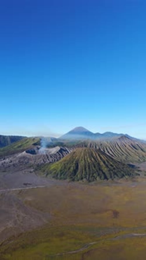 Vertical, aerial: Mount Semeru erupting above Bromo Caldera during the day in East Java