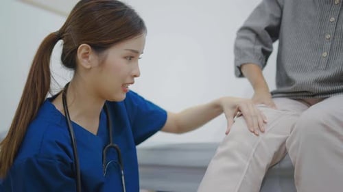 Adult Female Doctor Examines Patient's Knee in Hospital