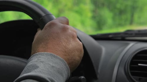Männliche Hände halten Lenkrad in der Nähe, selbstbewusster Mann, der während der Fahrt ein Auto fährt, Seitenansicht