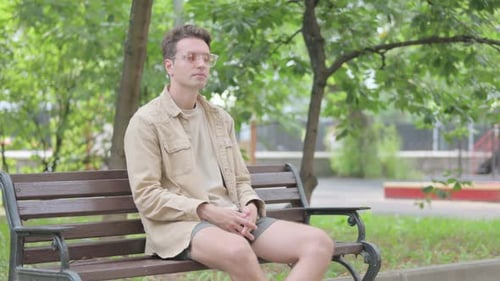 Young Adult Sitting on Park Bench in City