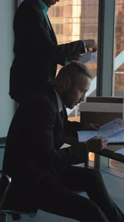 Vertical d'un entrepreneur déballant une boîte en carton avec des documents et dans un nouveau bureau