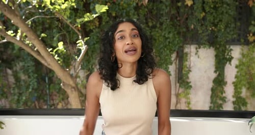 Woman Talking and Gesturing in Front of Greenery