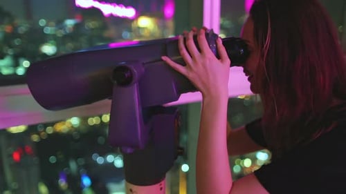 Woman Looks Through Telescope at City at Night