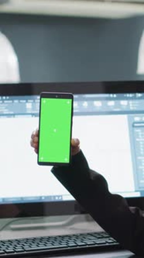 Hand Holding Smartphone with Green Screen in Office