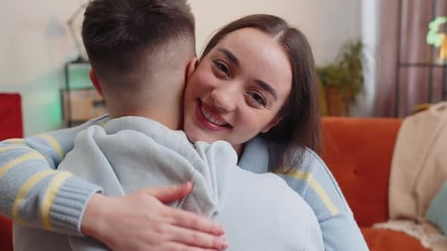 Happy Woman Hugs Young Man in Living Room