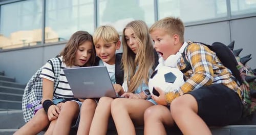 Group of teenage school children using laptop reading good news, celebration, rejoice, have fun