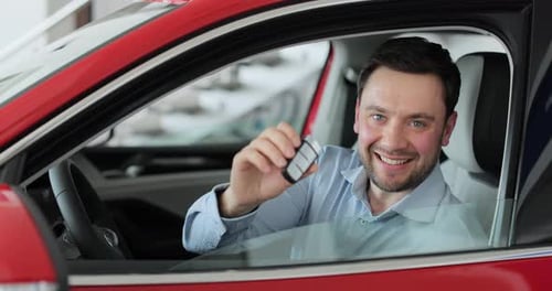 Young Man Showing Key to New Car Man Holding Car Keys at the Dealership Salon Auto Business Concept