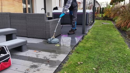 Man Cleans Patio with Pressure Washer Tool Outdoors