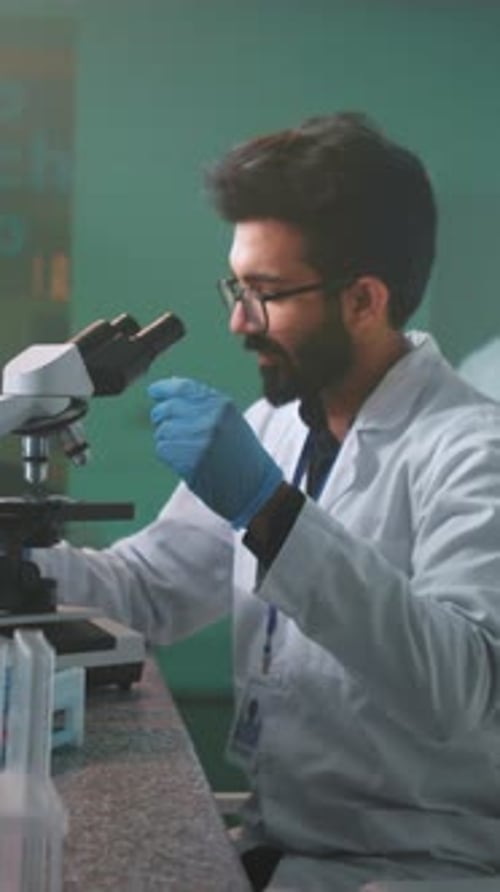 Scientist Examining Sample Under Microscope in Lab