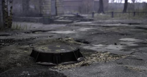 Stadtlandschaft mit einem vernachlässigten Kanaldeckel in einem bewachsenen Gebiet