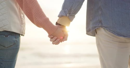 Couple, sunset and holding hands at beach for love, care and romance outdoor