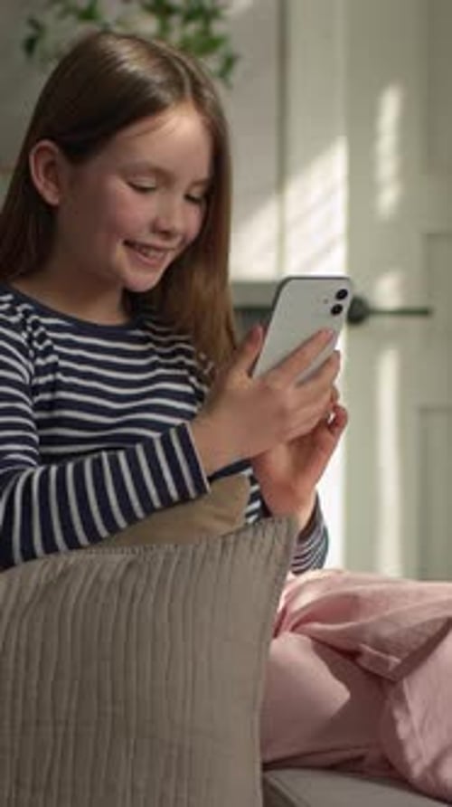 Smiling Girl Using Cellphone While Sitting on Couch