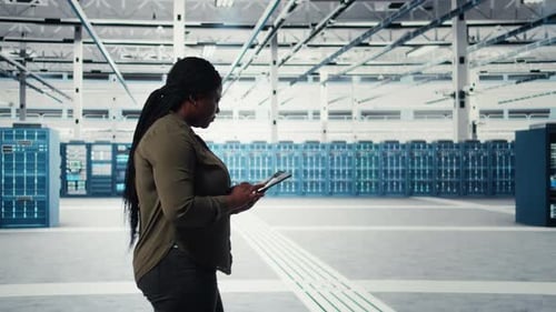 Smiling Engineer Walking in Data Center with Laptop Checking Hardware